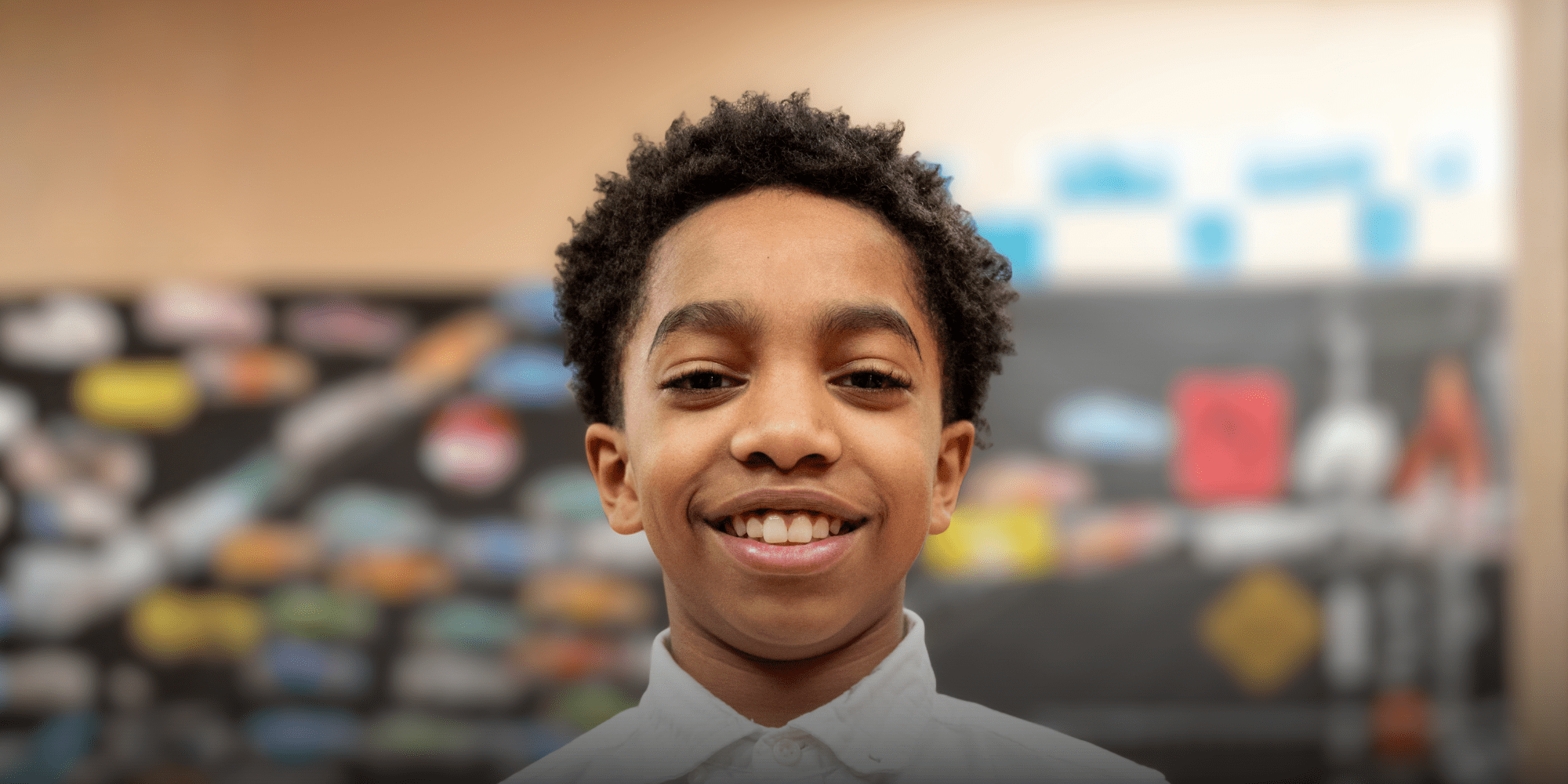 Smiling student in a white collared shirt in a classroom.